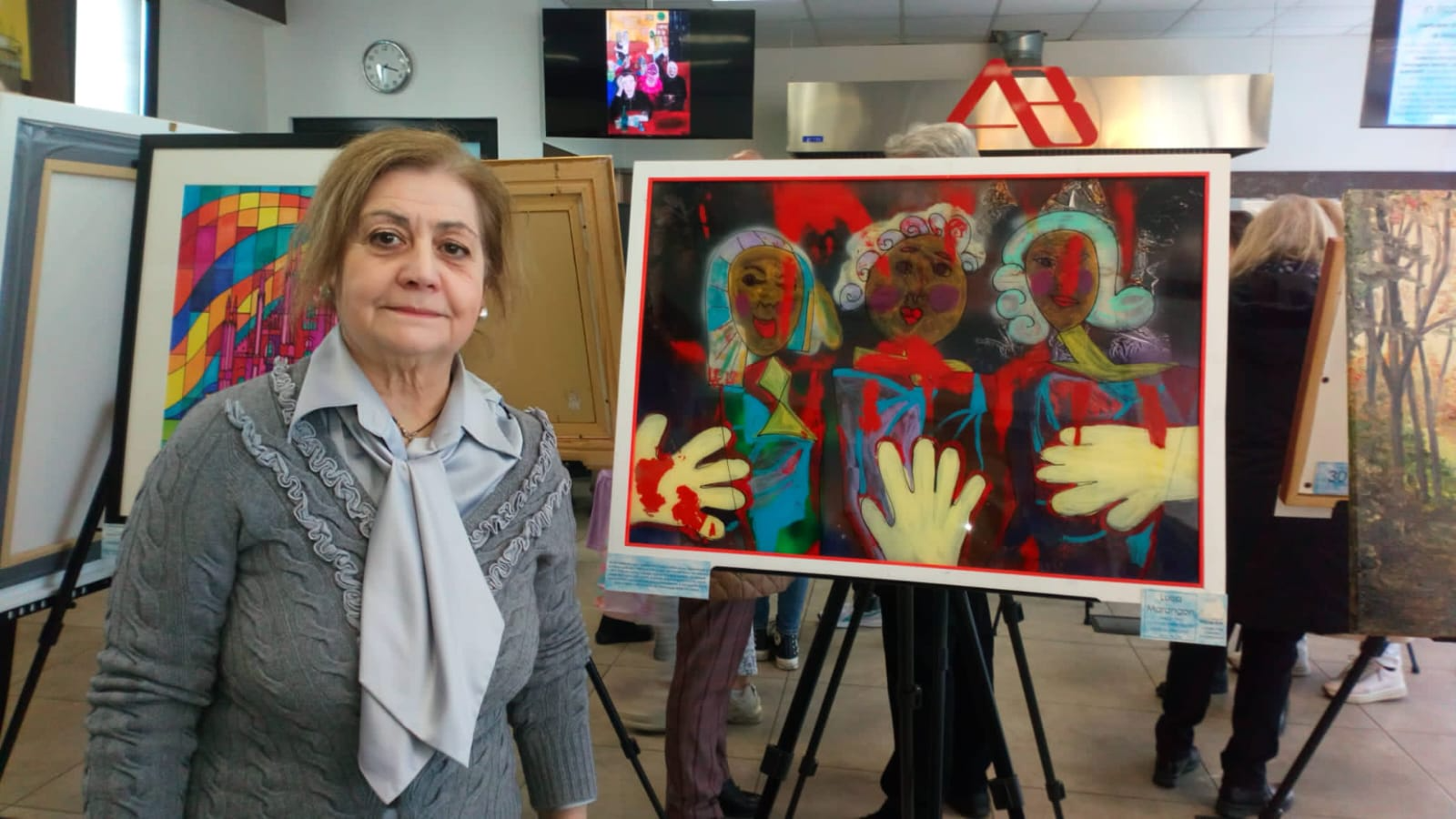 Insegnante di pittura adulti accanto alle sue opere